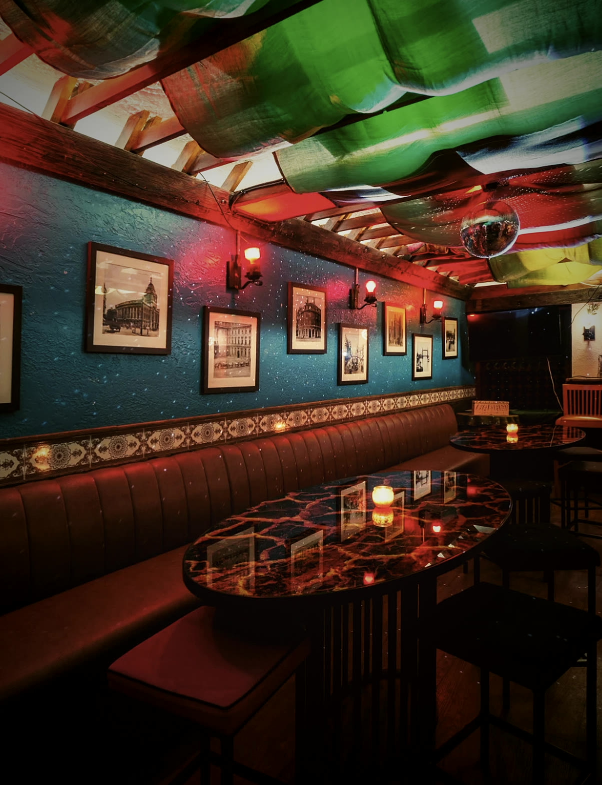 The basement event space: booth seating under draped fabric ceilings, with framed Soho photographs on blue walls